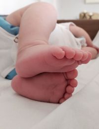 Low section of baby sleeping on bed