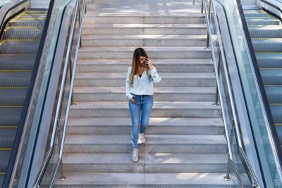 Businesswoman with glasses using smartphone while smiling, going down on metro. business concept