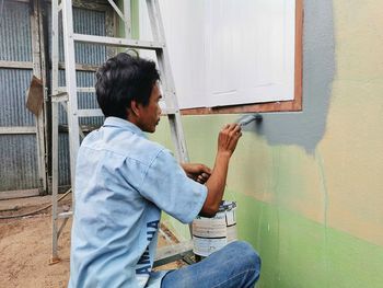 Rear view of man working on wall