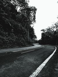 Road amidst trees against clear sky