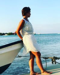 Side view of woman standing by boat at beach against sea