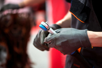 Midsection of man wearing gloves while holding equipment