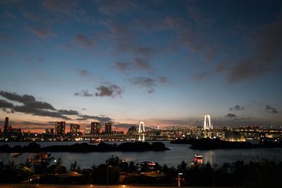 Illuminated rainbow bridge over tokyo bay against sky during sunset