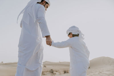 Rear view of father with son while standing in desert