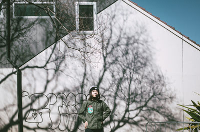 Portrait of man standing by bare tree against sky