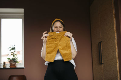 Woman in bedroom holding baby trousers