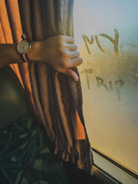 Midsection of woman standing by window