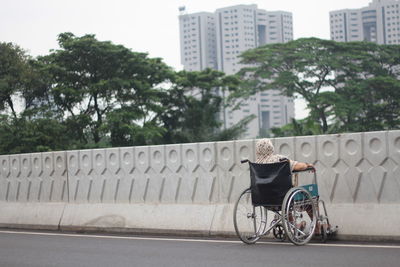 Rear view of woman sitting on wheelchair at road