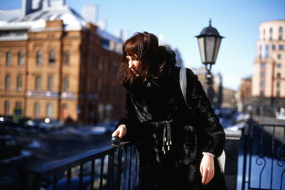 Woman standing by railing in city