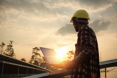 Low angle view of man standing against sky during sunset