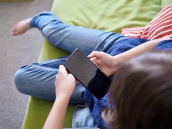 Midsection of woman using mobile phone while sitting on sofa at home