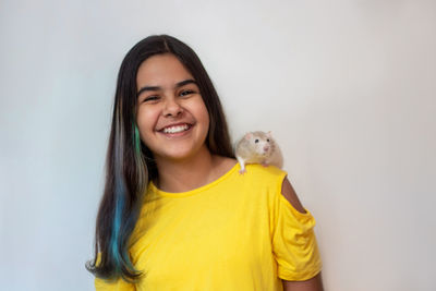 Portrait of smiling teenage girl with rat against white background