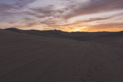 Foot prints and tire tracks on sand in desert