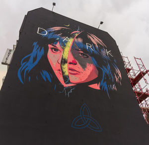 Low angle view of graffiti on wall against sky