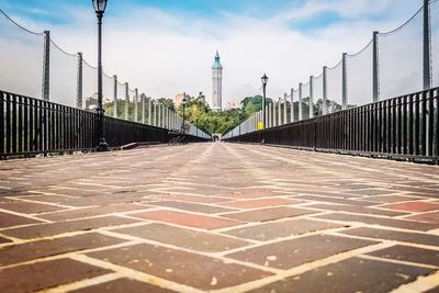 Walkway in city against sky