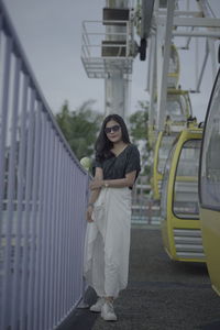 Portrait of young woman standing on railing