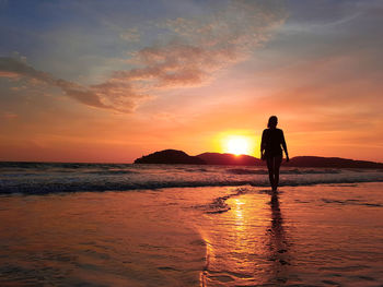 Silhouette person standing on beach against sky during sunset