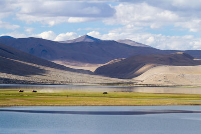 Scenic view of lake by mountains against sky