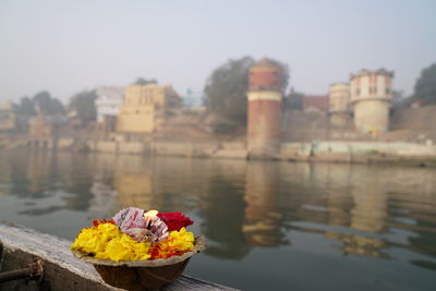 Flowers blow on boat by lake against sky