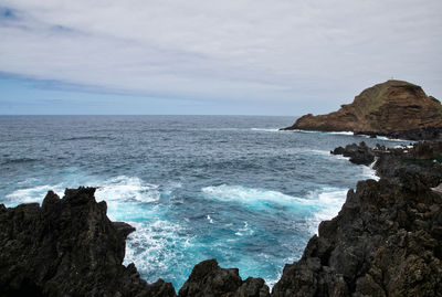 Scenic view of rocks in sea against sky