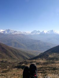 Low section of person on mountain against clear sky