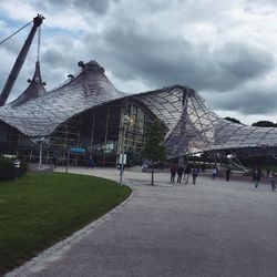 People walking on landscape against cloudy sky