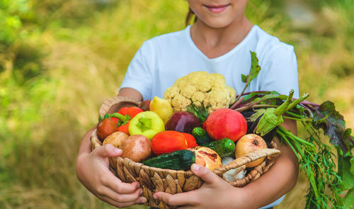 Midsection of woman holding fruits in basket