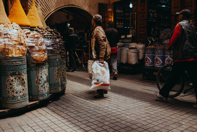 Rear view of people walking on street in city