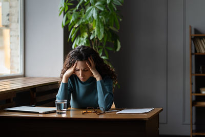 Exhausted woman sit at desk with closed laptop tired of overwork, burnout and lack of inspiration