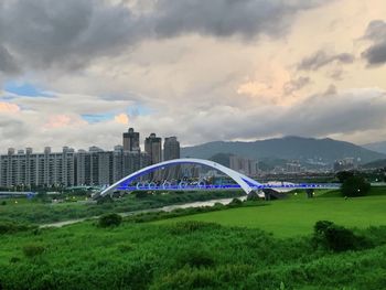 Arch bridge on field against sky in city