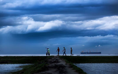 People standing by sea against sky