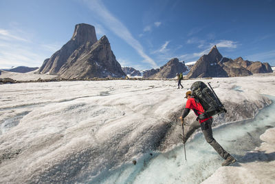 Man walking on snow covered mountain against sky