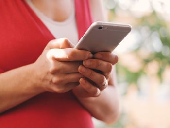 Midsection of woman using mobile phone while standing outdoors