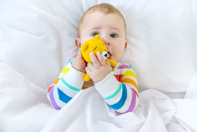 Portrait of cute baby girl lying on bed at home