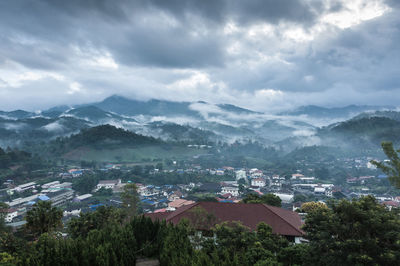 Aerial view of townscape and mountains against sky