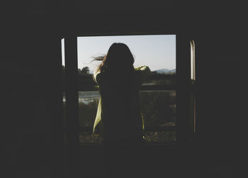 Rear view of silhouette woman standing against sky
