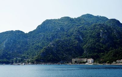 Scenic view of sea by mountain against clear sky