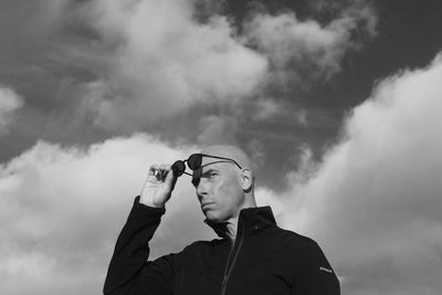 Low angle view of man photographing against cloudy sky