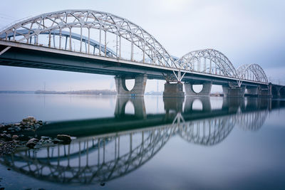 Reflection of arch darnytskyi bridge against sky