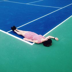 High angle view of woman sleeping at tennis field