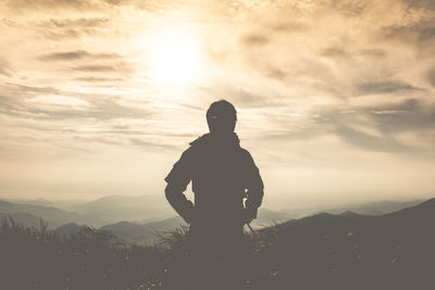 Silhouette man standing on mountain against sky during sunset
