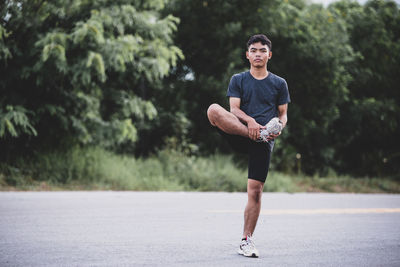 Full length of young man looking away while walking on road