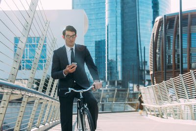 Full length of young man with bicycle against building in city