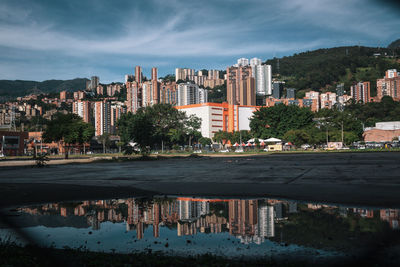 Buildings by lake against sky in city