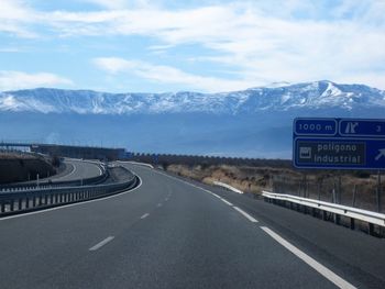 Road sign by mountains against sky