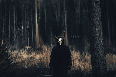 Person wearing taxidermy standing against trees in forest