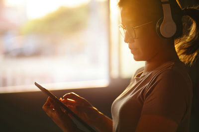 A woman uses a tablet during listening to music with the headphone