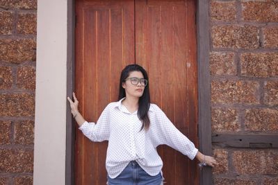 Portrait of smiling woman standing against brick wall