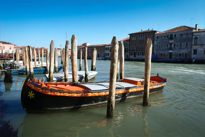 Boat moored in canal against clear sky