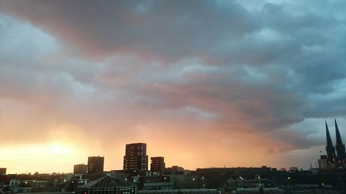 Cityscape against cloudy sky at sunset